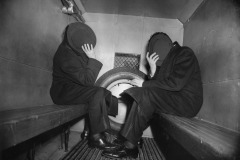 Shameful Arrest. Charles Sodokoff and Arthur Webber use their top hats to hide their faces as the police van takes them away. The two Brooklynites were arrested for being drunk and disorderly and assaulting a police officer in the Astor Bar, New York. By Weegee (Arthur Fellig).
