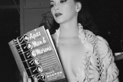 A Good Read. A revealingly dressed showgirl, Sherry Britton, reads Earnest Albert Hooton\'s Apes Men and Morons. circa 1950. By Weegee (Arthur Fellig).